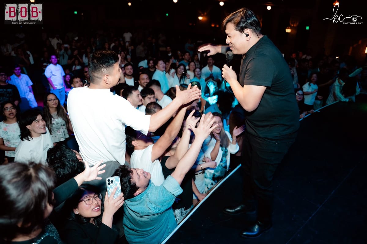 A singer leaning off the stage to high-five the crowd at a packed B.O.B Events show