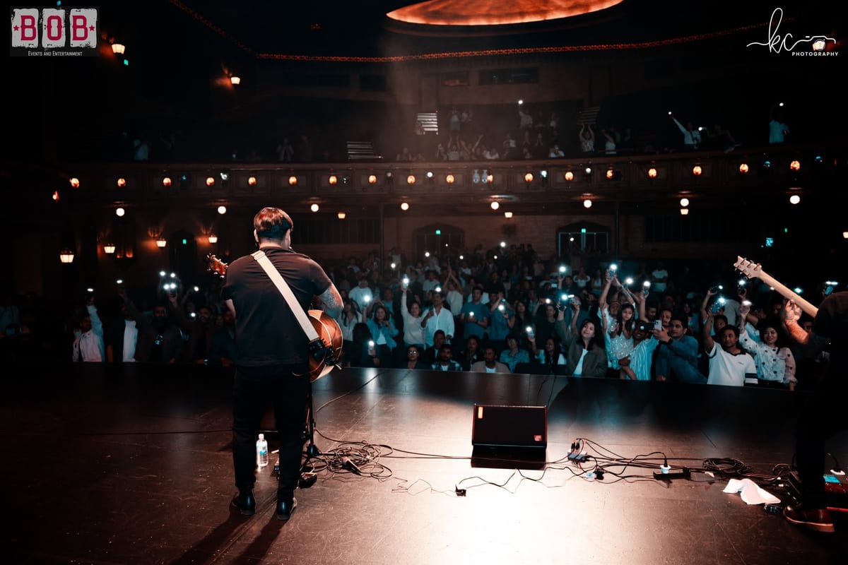 A guitarist's view from the stage over a packed crowd holding up phone lights