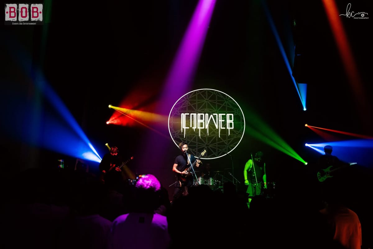 The Cobweb logo lit up on stage in coloured lights at Rock Fest Vol. 1